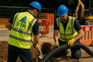 Two DTK Group civil engineers installing ducting in an excavated trench on an active infrastructure site