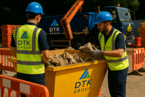 DTK Group workers collecting bricks and rubble into a branded yellow skip at a construction site